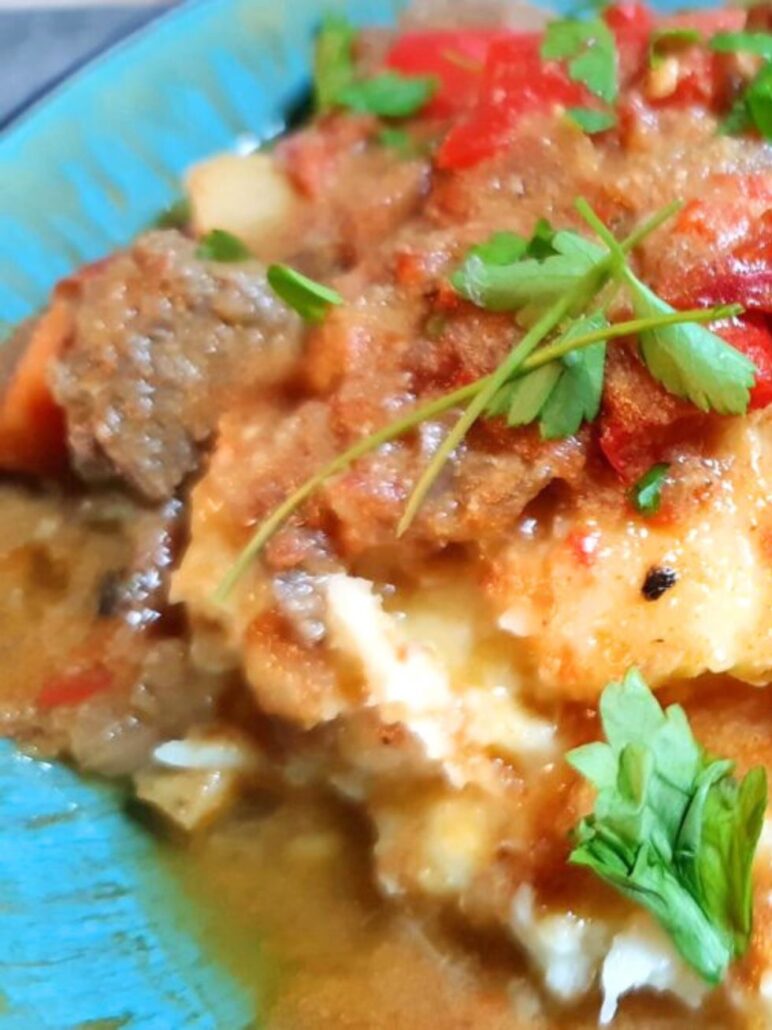 Rindergulasch mit Kartoffelstampf angerichtet auf einem tiefen Teller